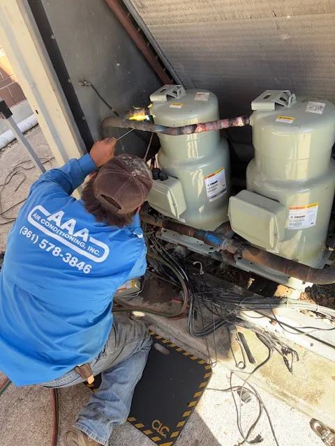 AAA Air Conditioning technician brazing refrigerant lines on commercial condensing equipment