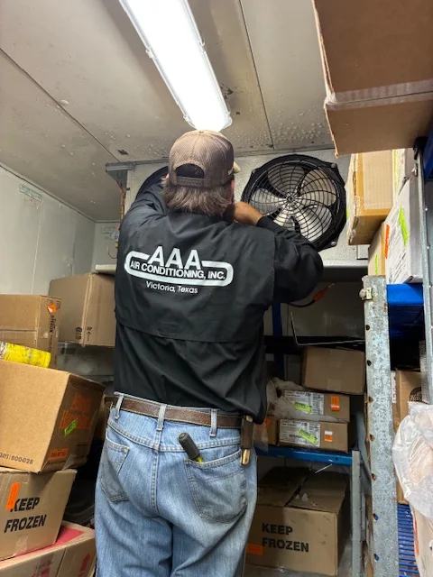 Technician installing an evaporator fan inside a walk-in cooler